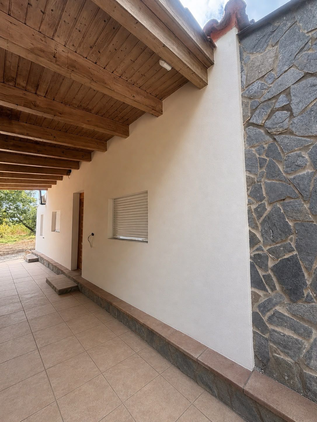 Detalle de una fachada terminada junto a un muro de piedra